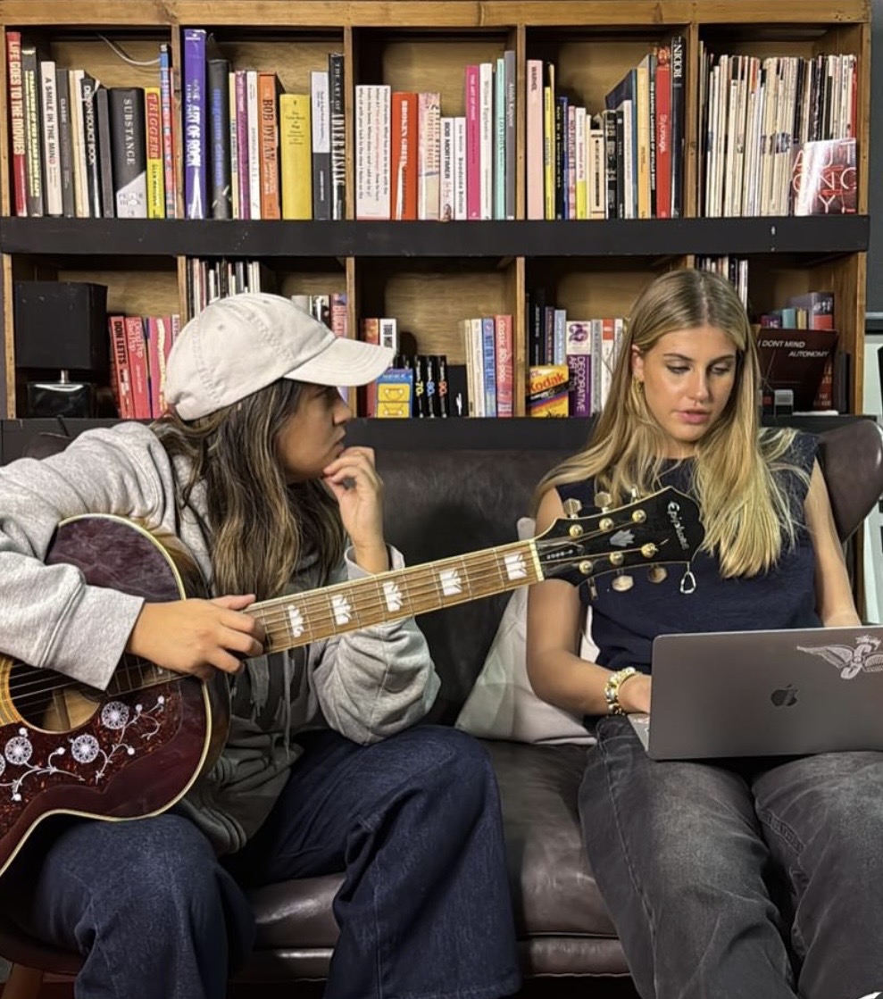 A young artist with her guitar working through the week's plan with her manager on a laptop