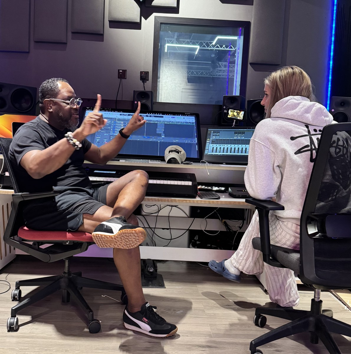A producer talking through a session with a young artist in a recording studio
