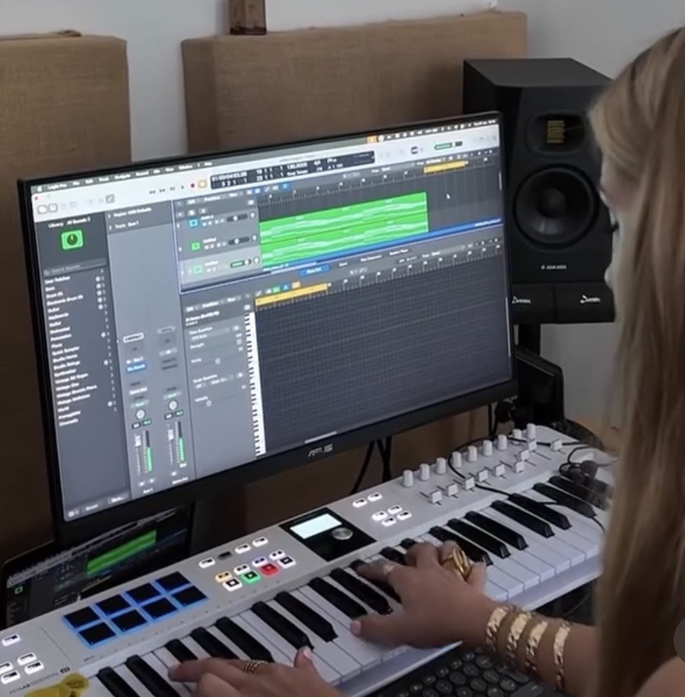 A young artist writing a song at her keyboard and DAW in a home studio